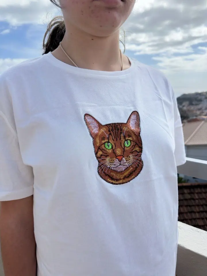 Founder of Embroidery Madeira wearing a t-shirt embroidered with a cat portrait, with a view over Funchal